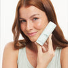Woman holding C-esta® Face Serum with a plain background
